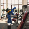 Mitarbeiter im blauen Ganzkörperschutzanzug reinigt Fitnessstudio