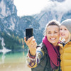 Lächelnde Frau und Kind machen ein Selfie vor einem Bergsee