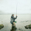 Angler steht im Wasser bei grauen Wetter