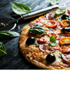 Bild einer Pizza mit Oliven, Tomaten, Salami und Basilikumblättern sowie ein Pizzaschneider