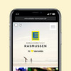 Smartphone zeigt Website edeka-rasmussen.de mit Foto vom Strand