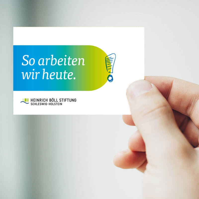 Hand hält Visitenkarte der Heinrich Böll Stiftung