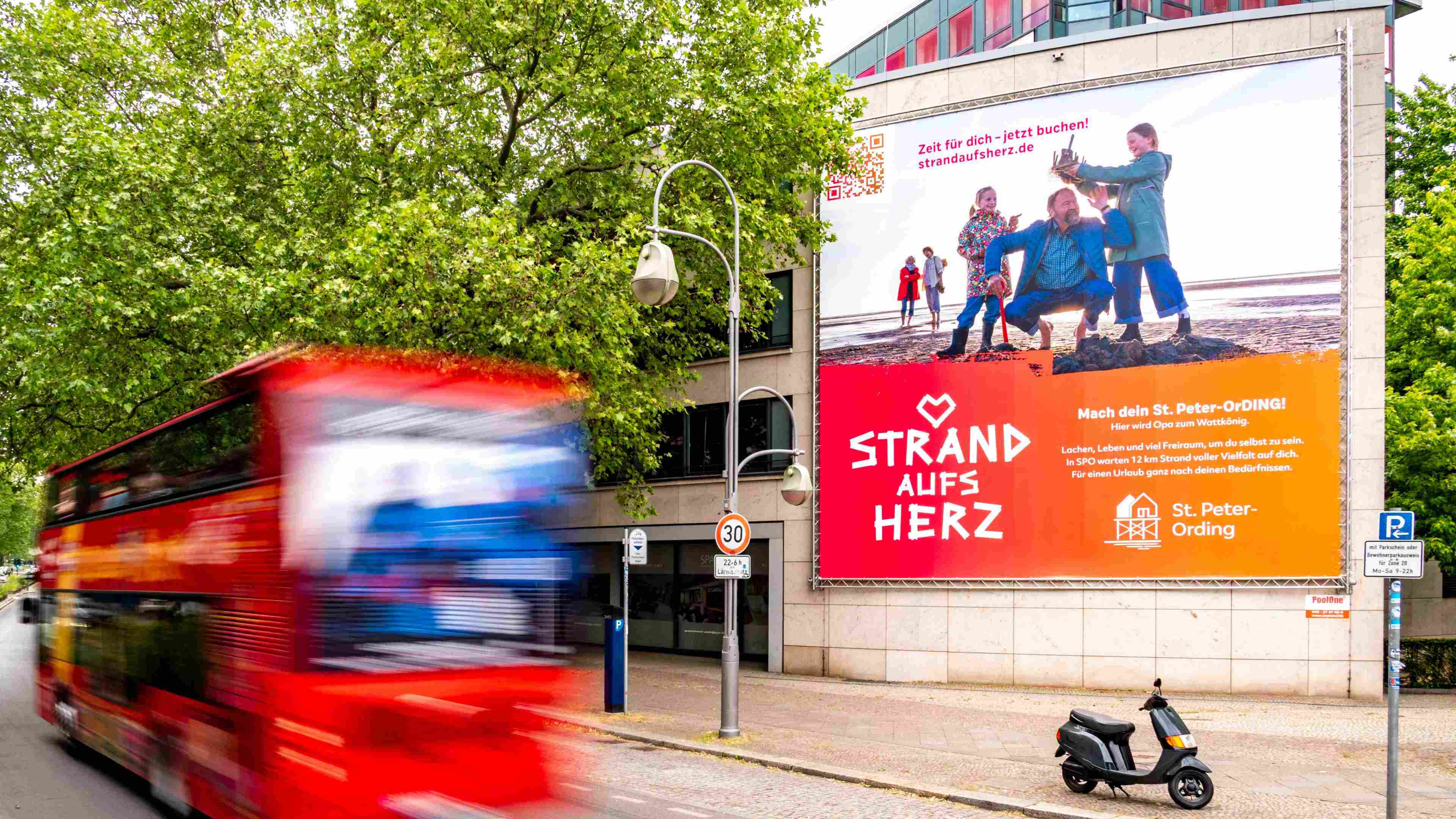 Strand aufs Herz Plakat in einer Straße mit vielen Bäumen