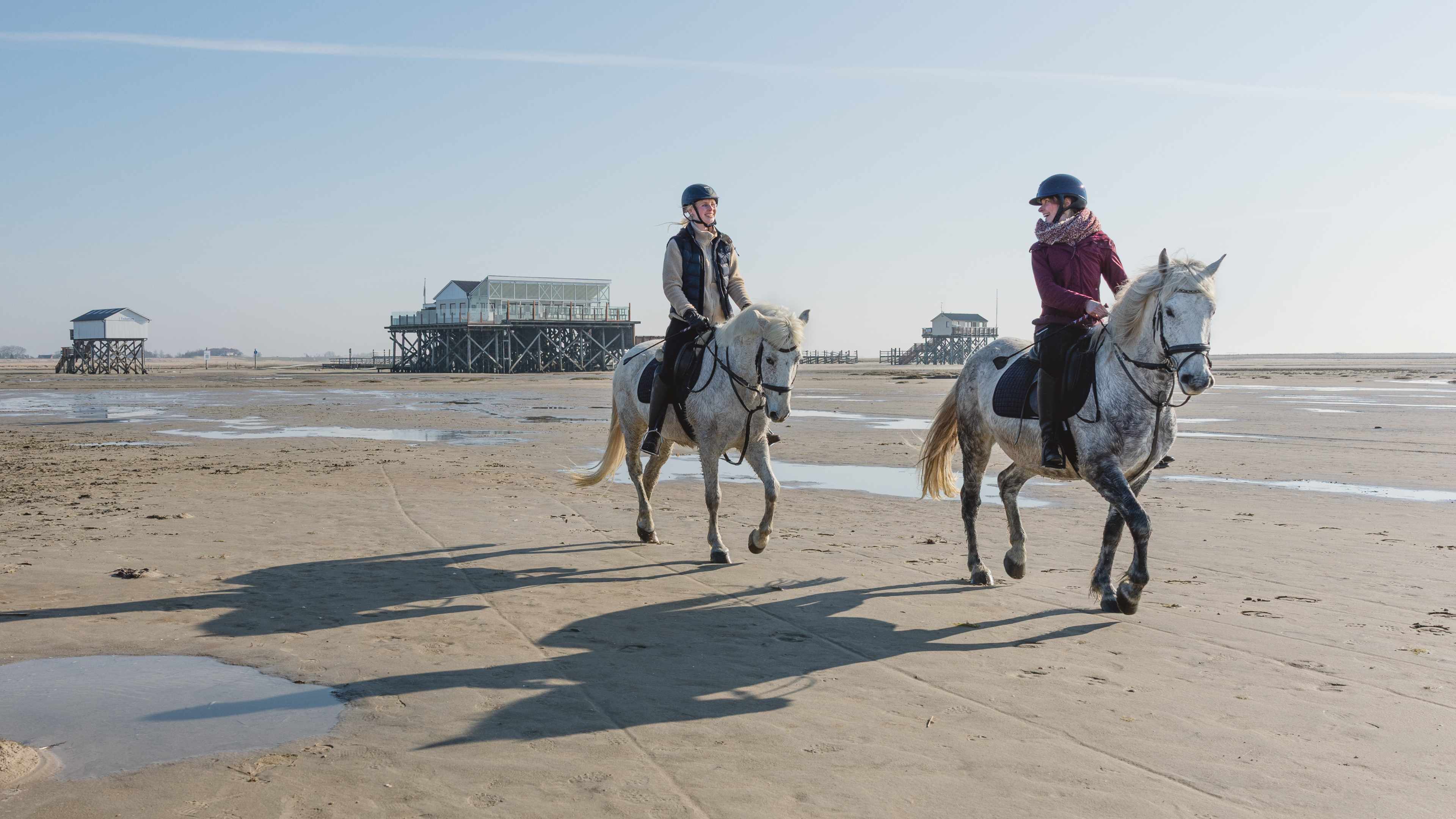 Zwei Frauen reiten auf Pferden am Strand