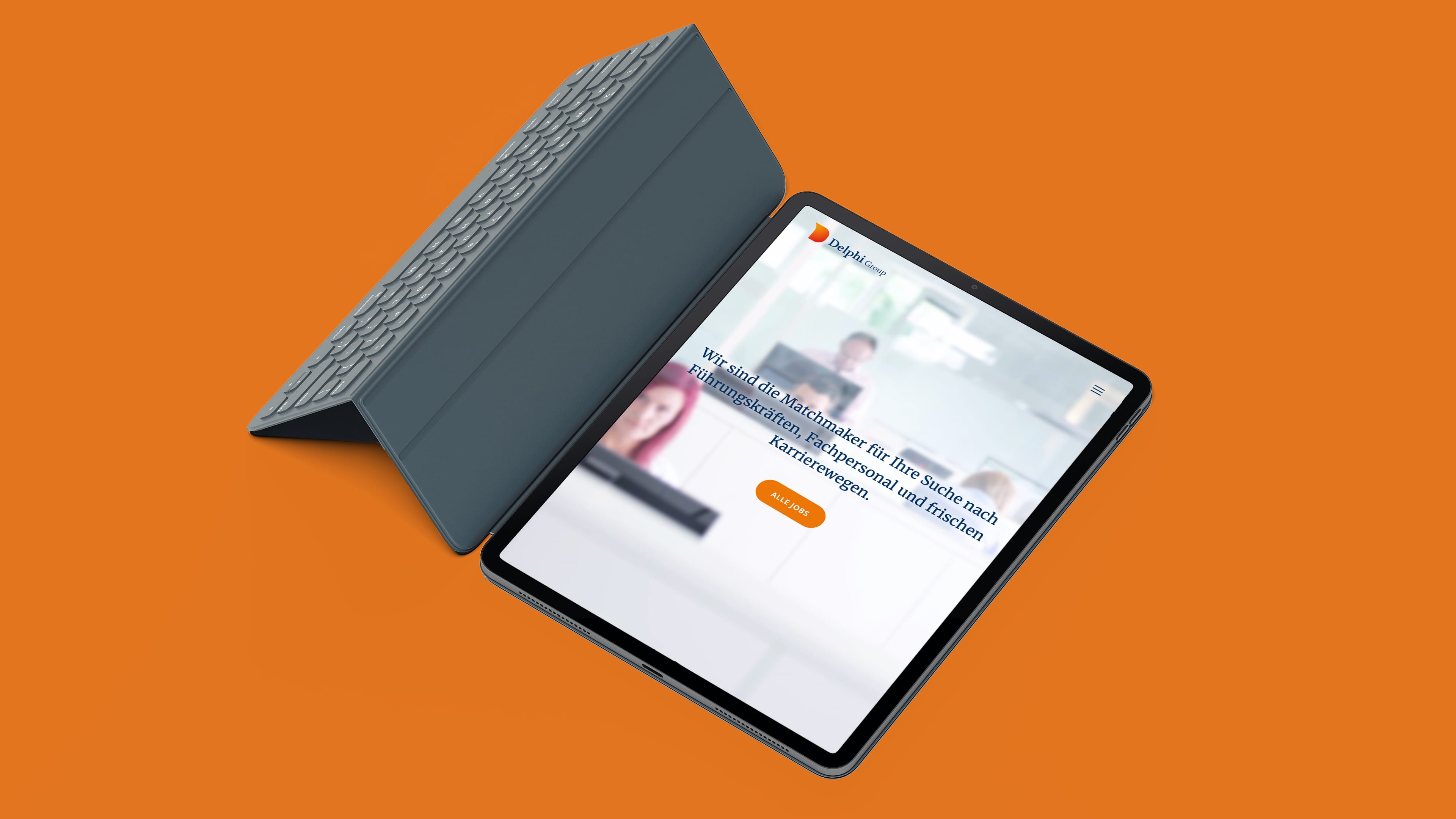 Tablet mit Tastatur zeigt Website der Delphi Group vor orangenem Hintergrund, Text "Wir sind die Matchmaker für Ihre Suche nach Führungskräften, Fachpersonal und frischen Karrierewegen"