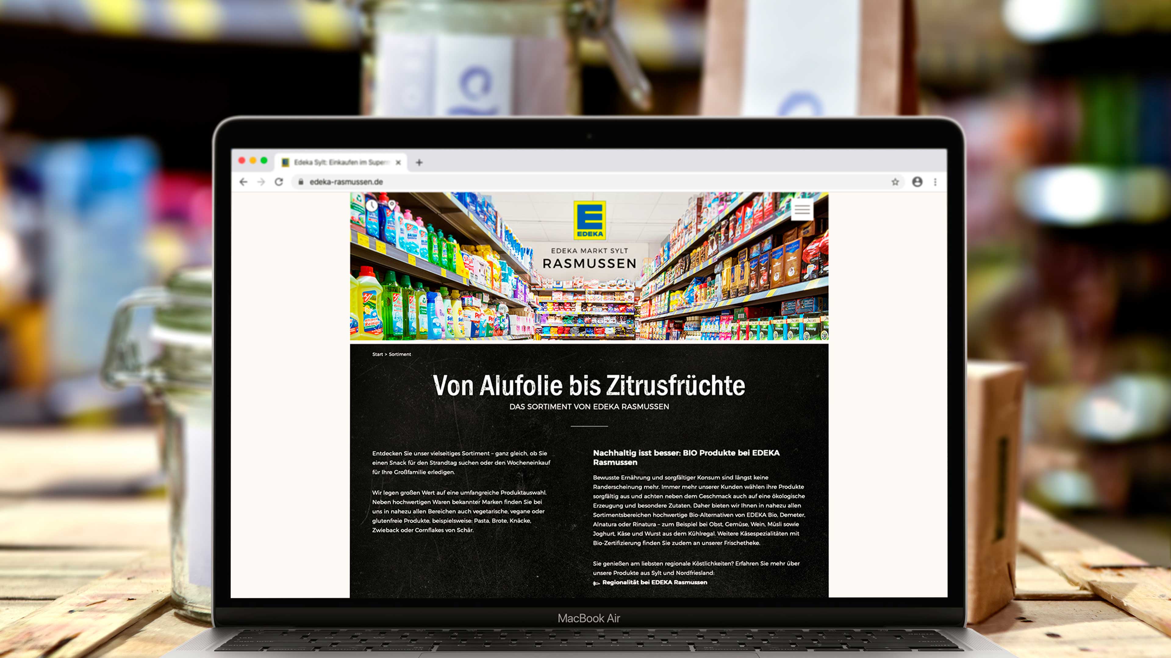 Laptop zeigt Website edeka-rasmussen.de mit Text "Von Alufolie bis Zitrusfrüchte"
