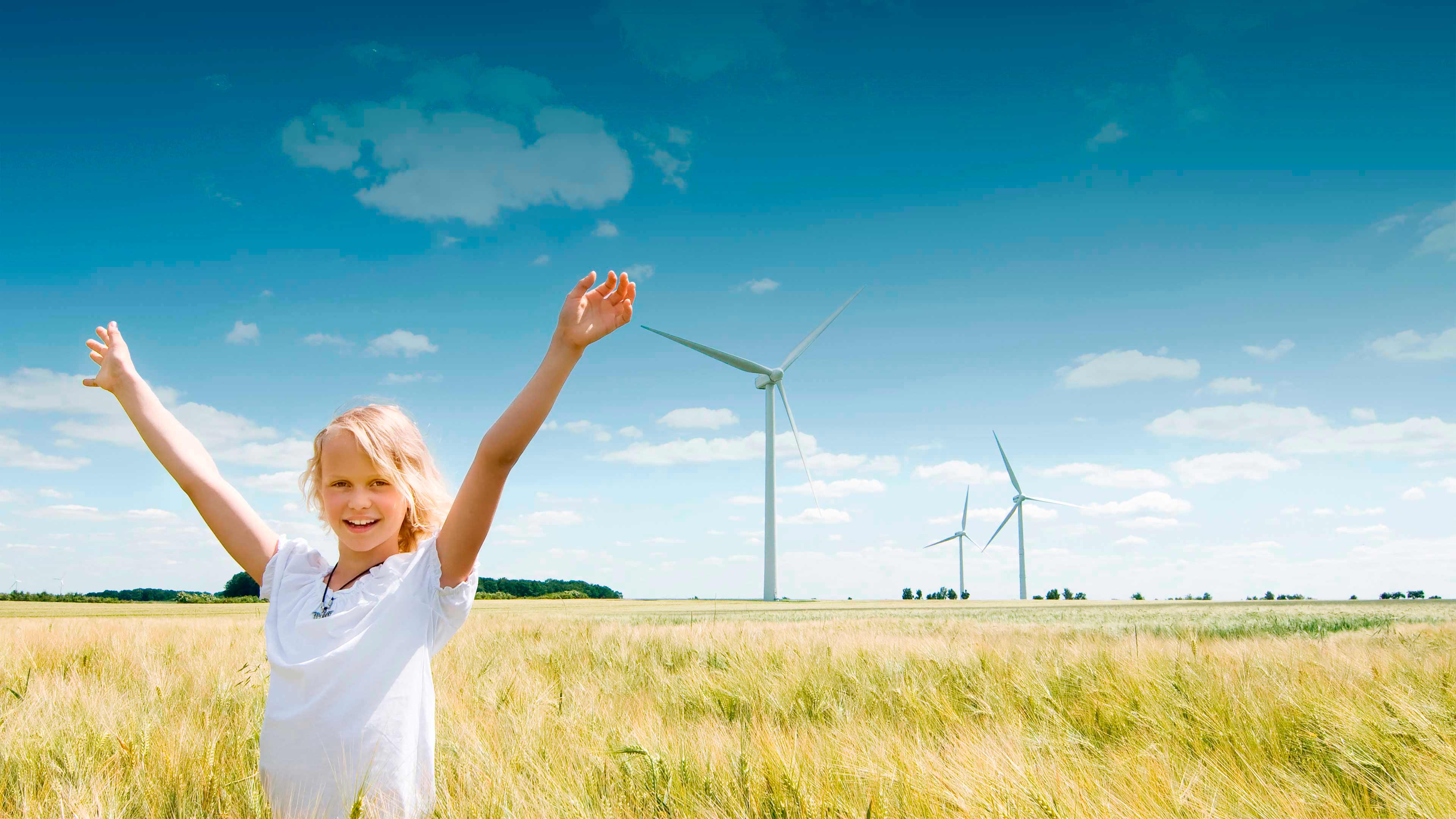 Blondes Mädchen steht in Kornfeld vor Windkraftanlage