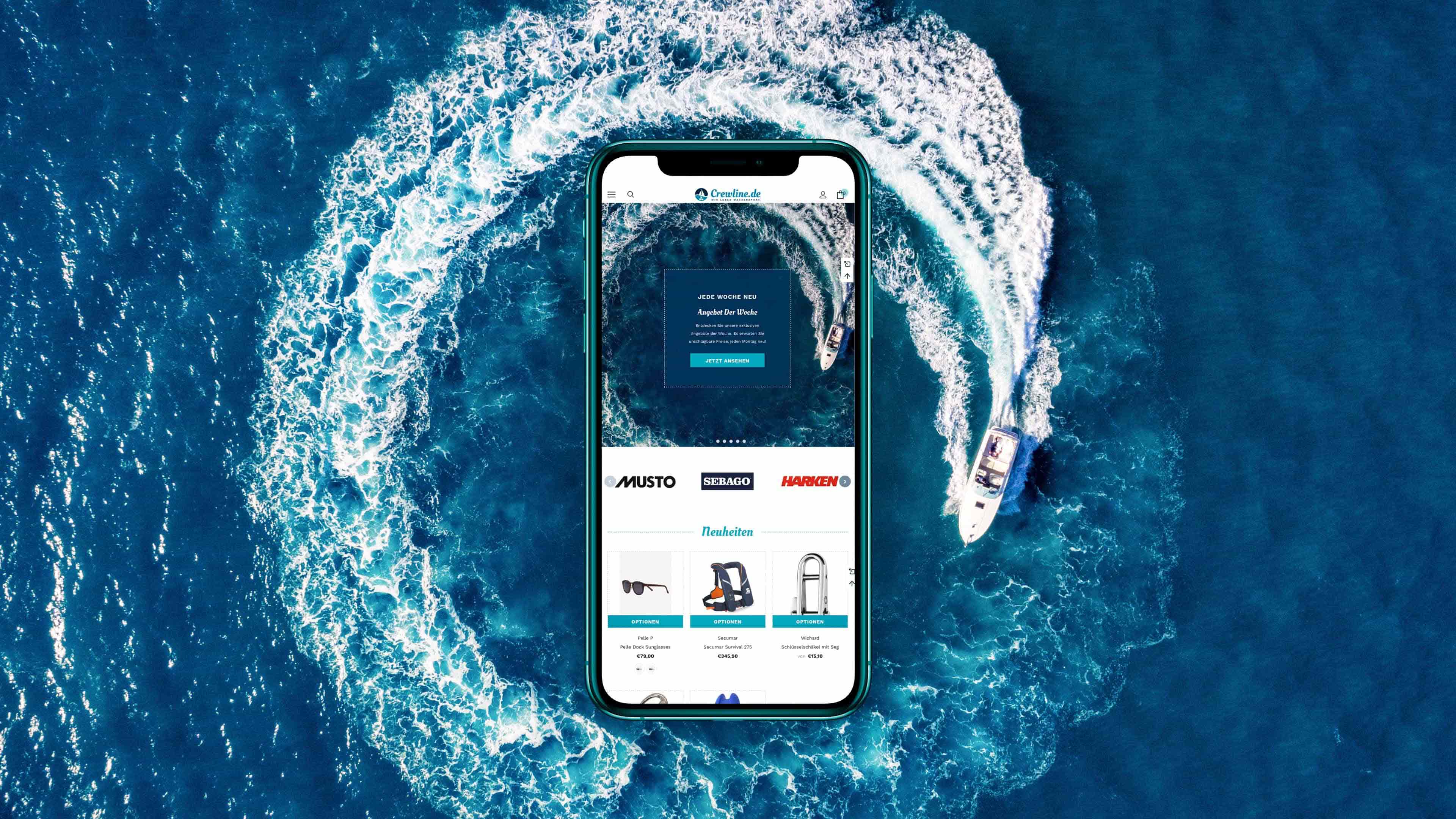 Smartphone zeigt Startseite von crewline.de vor Meereshintergrund