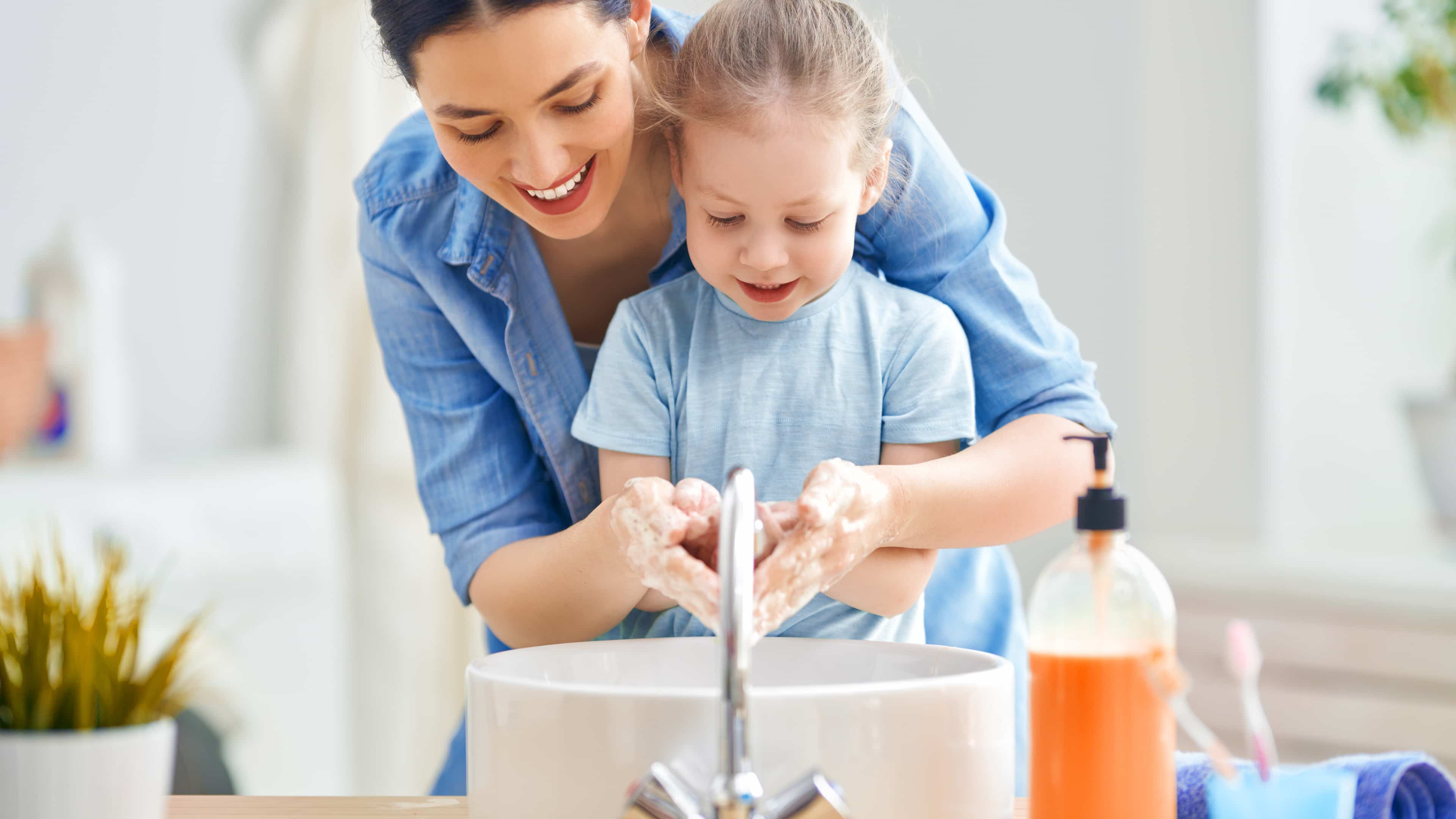 Eine Frau wäscht zusammen mit ihrer Tochter sich die Hände