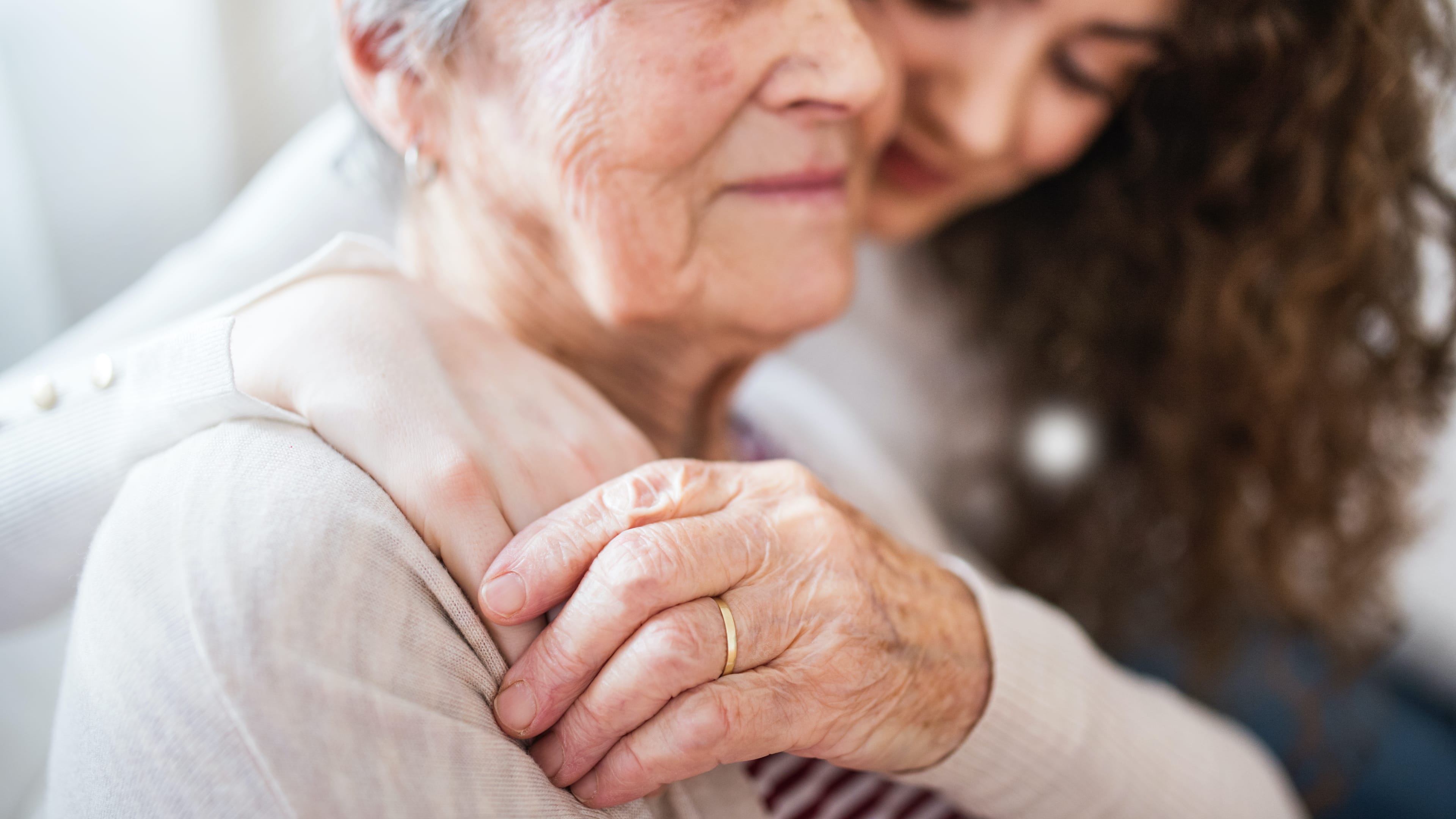 Eine junge Frau umarmt eine ältere Dame