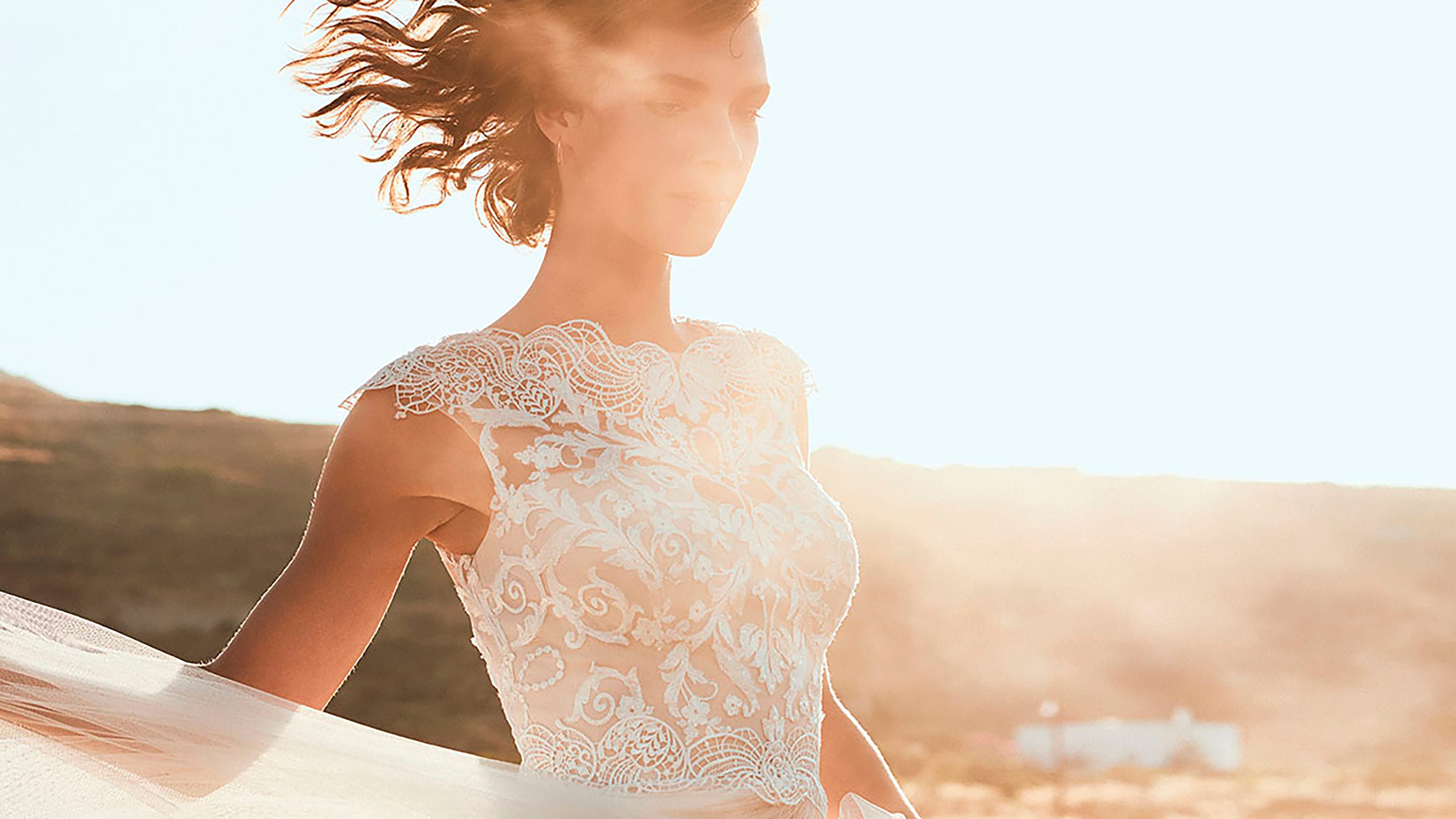 Frau in einem weißem Brautkleid posiert bei Sonnenuntergang vor der Kamera