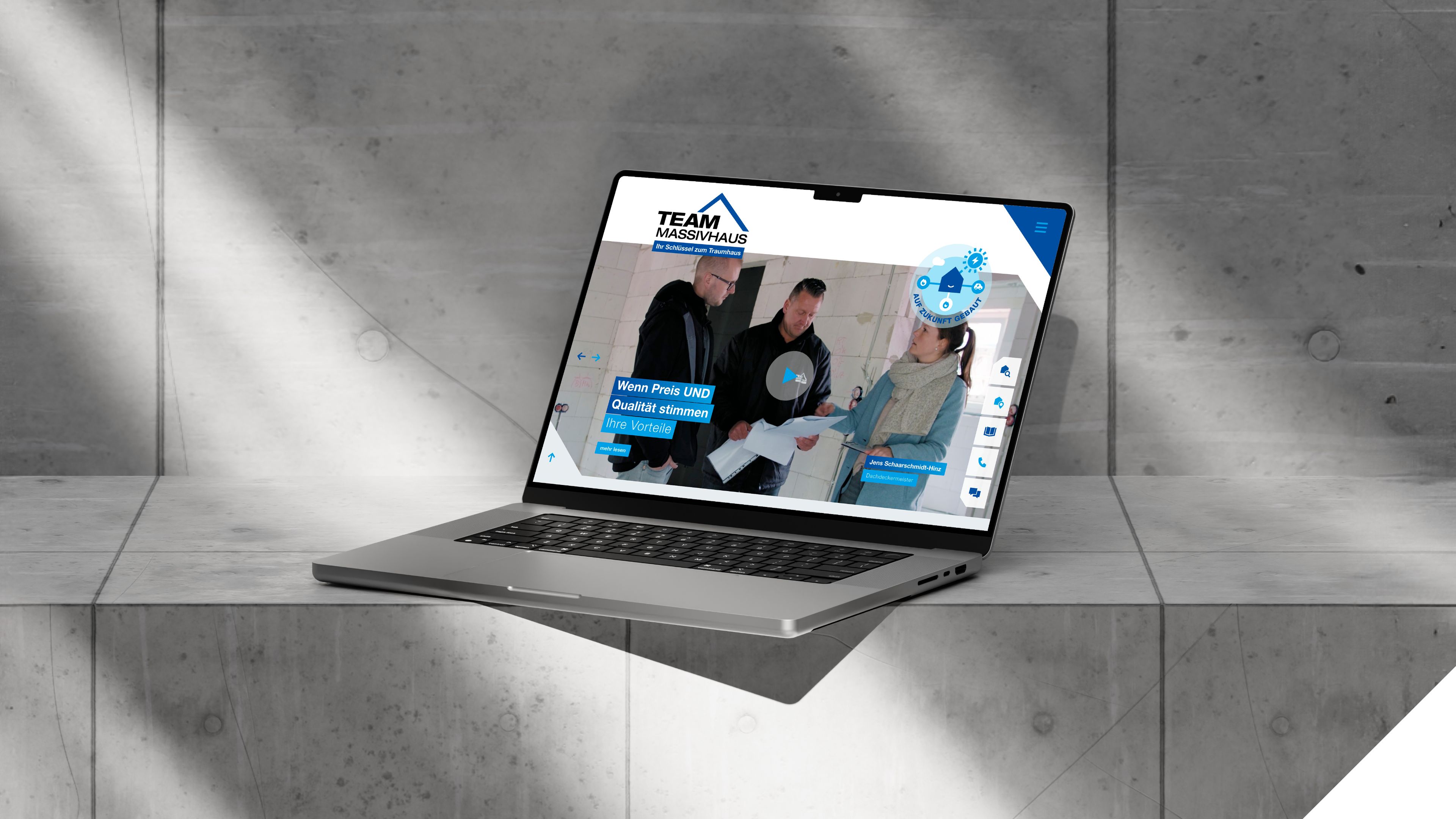 Aufgeklappter Laptop zeigt blauweiße Website von Team Massivhaus
