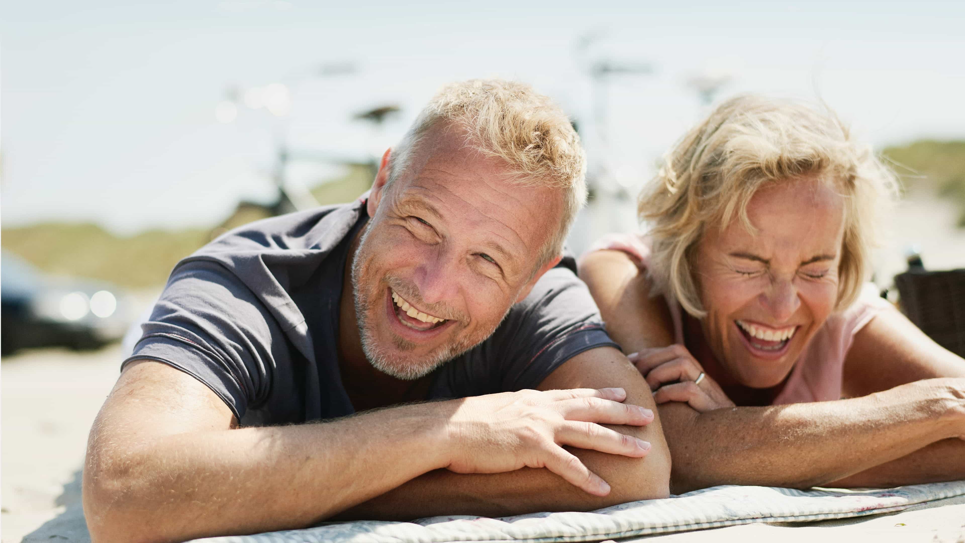 Älteres Ehepaar liegt auf Handtuch am Strand
