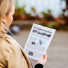 Eine Frau in brauner Jacke hält ein Magazin in der Hand