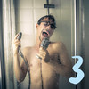 Ein Mann mit Brille singt unter der Dusche