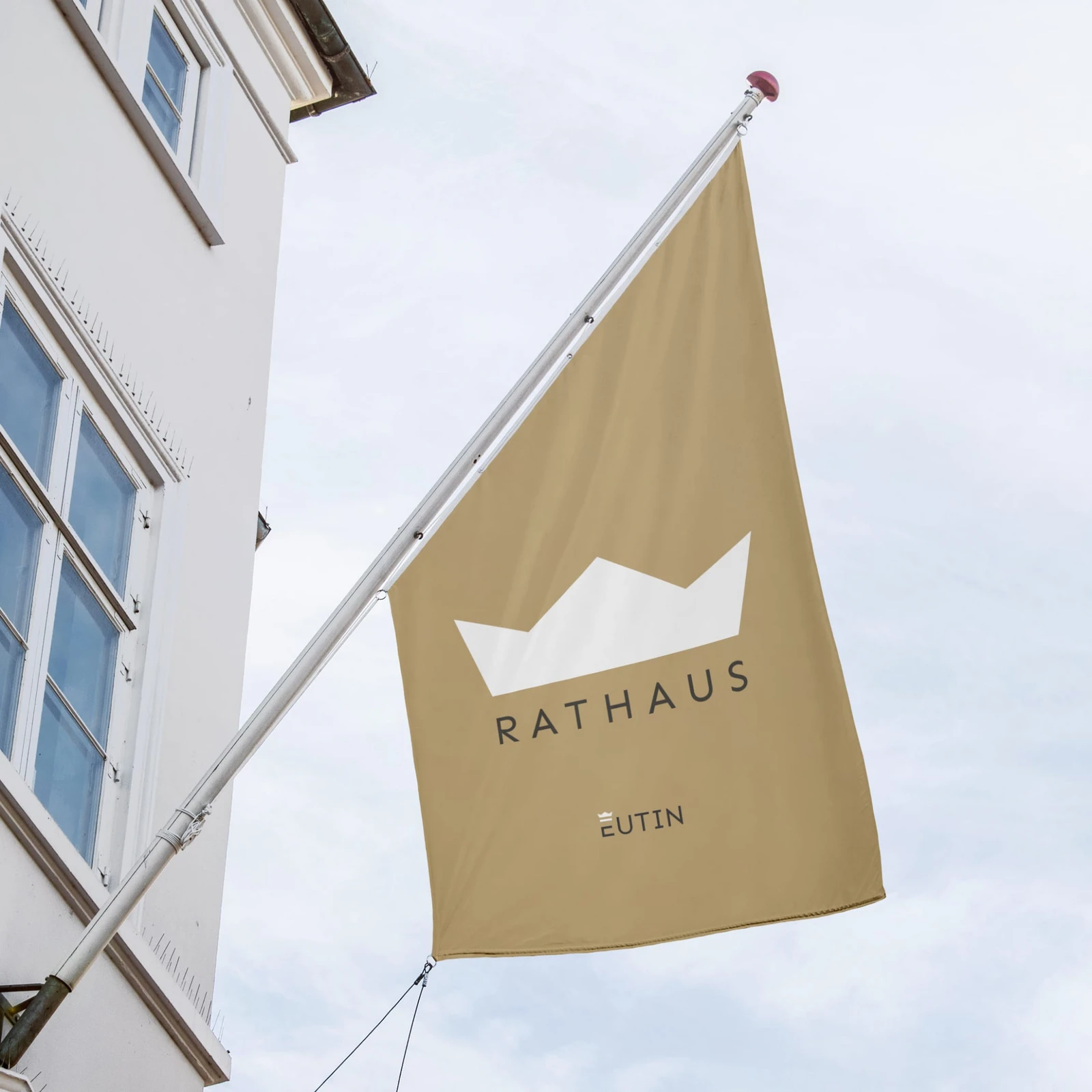 Fahnemast an Hausfassade mit Krone und Text 