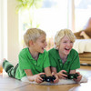 Zwei Kinder liegen in grünen Shirts auf dem Boden und spielen Playstation