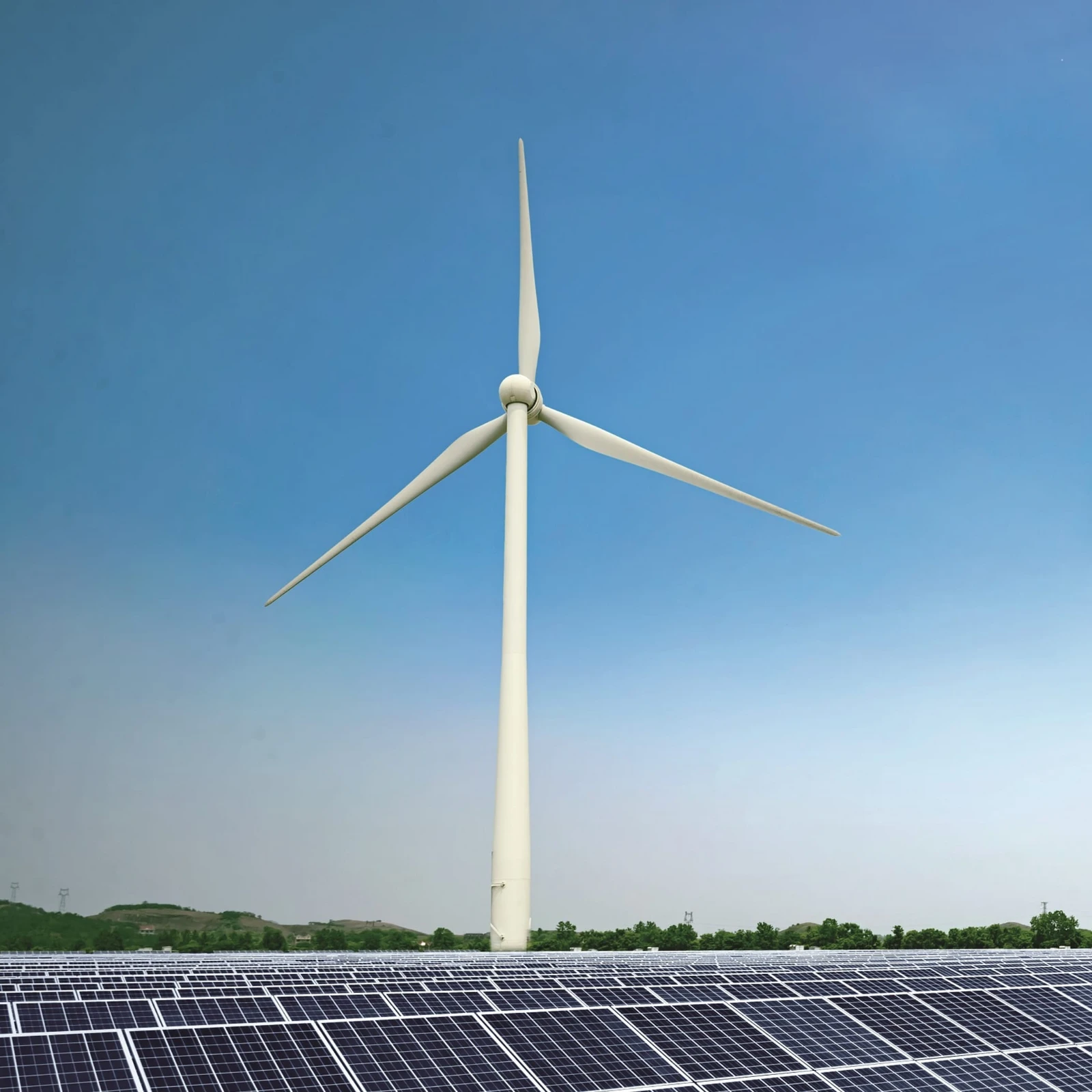 Blick auf ein Windrad mit Solaranlagen im Vordergrund