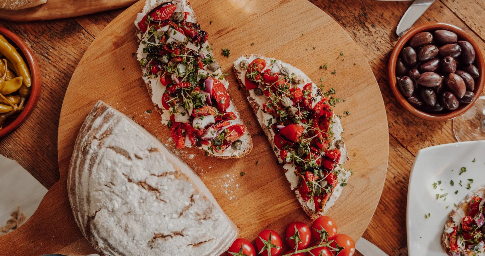h2_ellas_teaser_06.jpg Zwei Scheiben Brot mit pikanter Bruschetta belegt auf einem Holzbrett