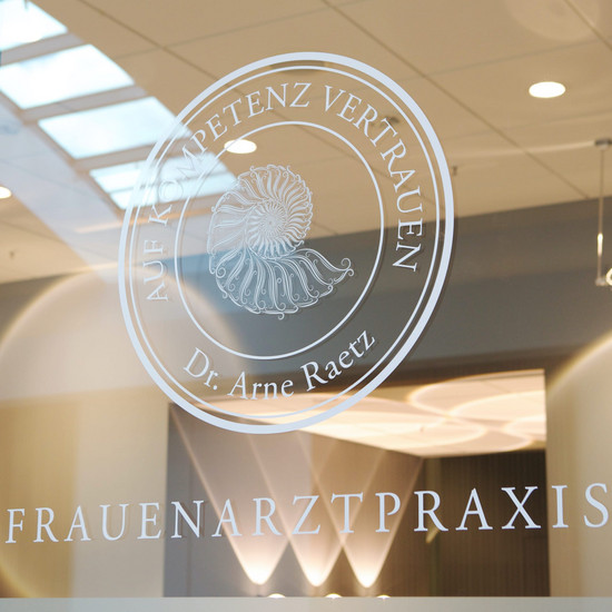 Rundes Logo der Frauenarztpraxis Dr. Arne Raetz auf Glasscheibe