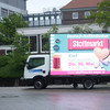 Weißer Lieferwagen mit pinker Werbung an der Seite