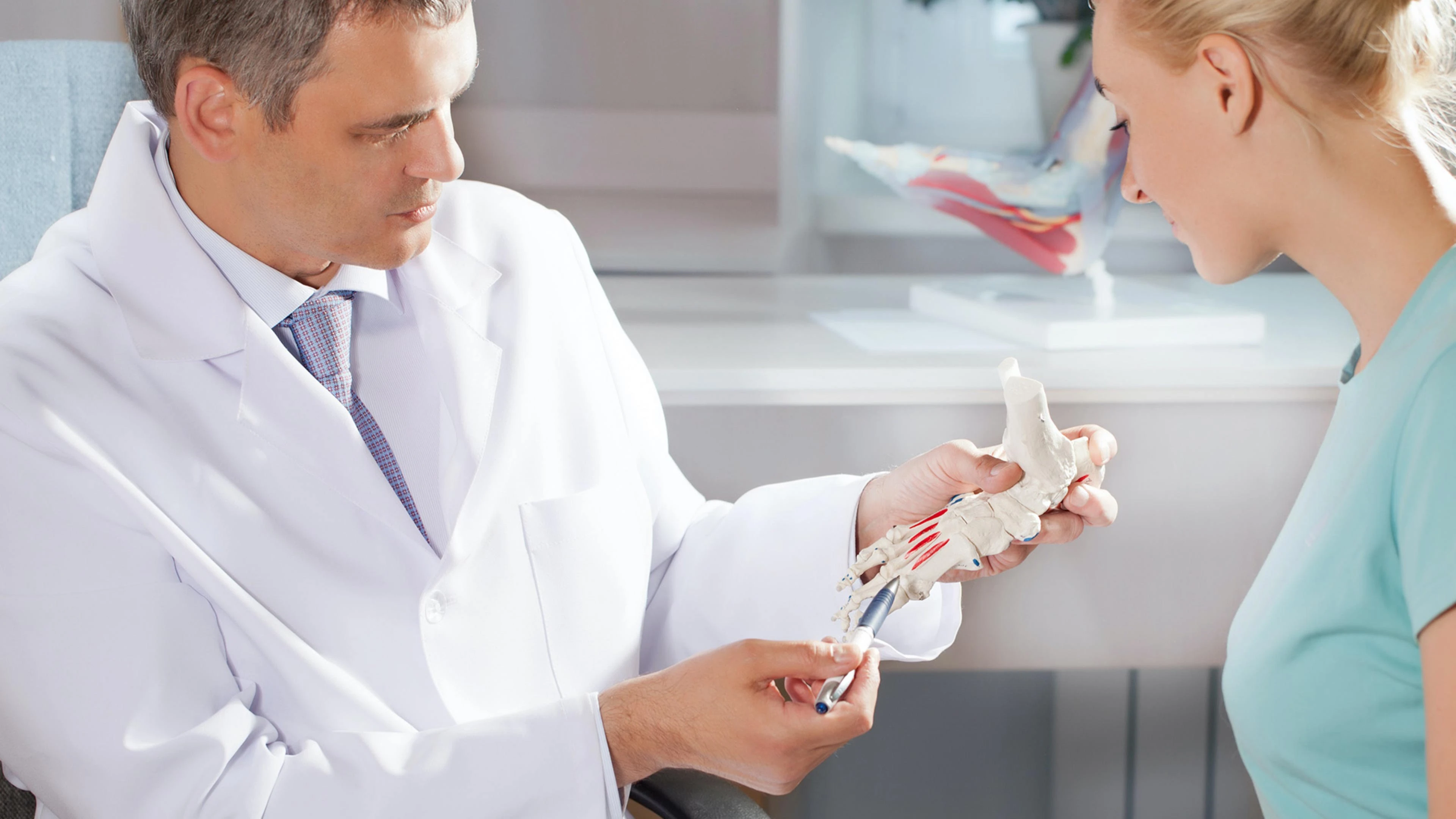 Arzt zeigt Patientin etwas am Knochen