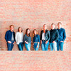 Teamfoto mit sieben Personen vor Klinkerwand