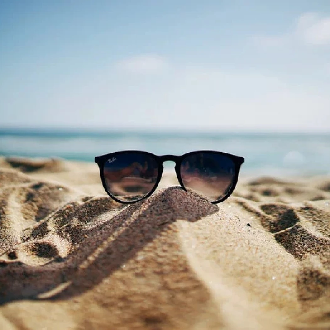 Foto einer Sonnenbrille im Sand am Strand