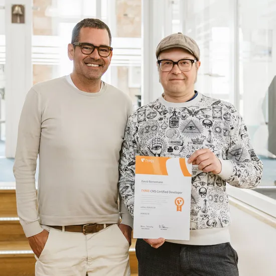 HOCHZWEI Geschäftsführer Felix mit unserem Kollegen, der sein Typo3 Zertifikat in die Kamera hält.