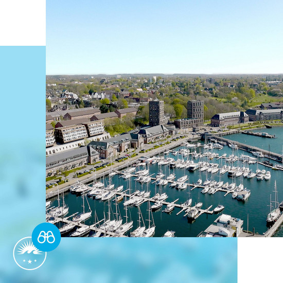 Luftaufnahme des Standortes Sonwik mit Yachthafen und Promenade mit blauem Rahmen und HOCHZWEI-Logo und Fernglas-Icon