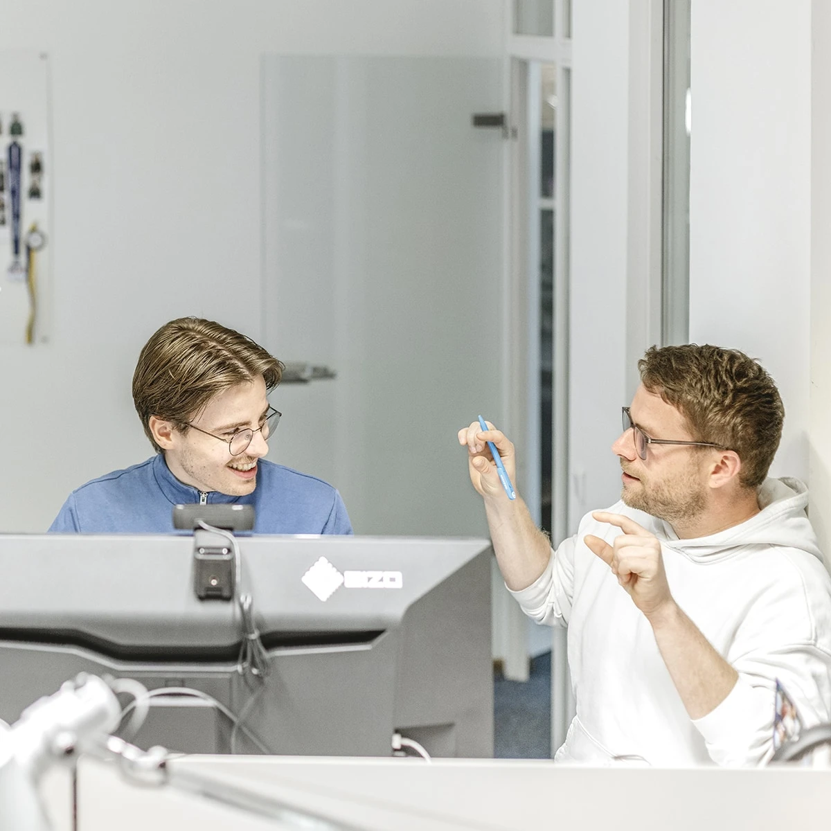 Zwei Grafiker im Arbeitsgespräch an einem Schreibtisch