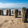 Alte Holzbohlen stecken im Strandsand
