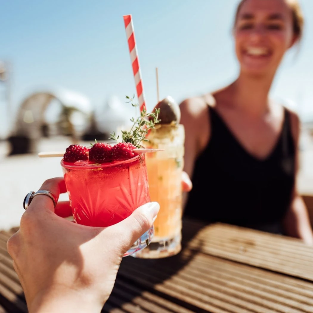 h2_tsg_teaser_10.jpg Eine Frau bekommt in einer Strandbar ein Getränk serviert