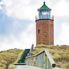 Ein Leuchtturm aus Backstein steht am Strand