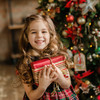 Junges Mädchen hält lächelnd ein rotes Geschenk in den Händen