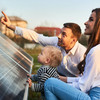Familie hockt vor einer Solaranlage