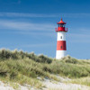 Rot weißer Leuchtturm steht am Strand
