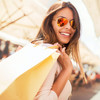 Frau mit Sonnenbrille trägt Shoppingtüten über der Schulter