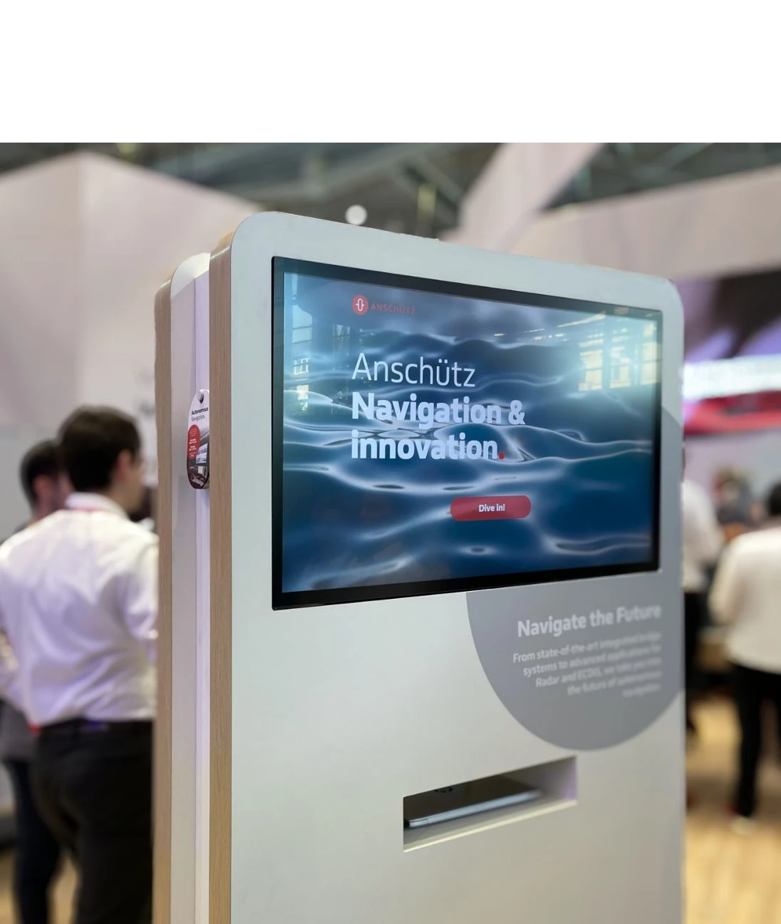 h2_messe_teaser_02.jpg Ein Messestand der Firma Anschütz mit einem großen Bildschirm.