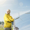 Ein Mann in gelber Jacke steht mit verschränkten Armen vor einer Solaranlage