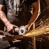 Ein Mann in Lederschürze schneidet mit einer Maschine in Holz