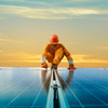 Installateur im orangenen Arbeitsanzug klettert auf einer Solaranlage