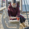 Eine Frau sitzt am Strand auf einer Bank