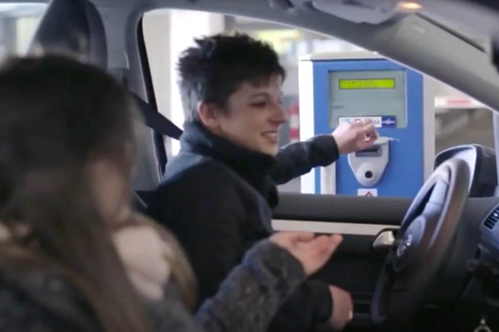 Eine Frau steckt ein Parkticket in einen Automaten
