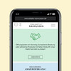 Smartphone zeigt Website edeka-rasmussen.de mit grüner Kachel