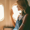 Blonde Frau sitzt am Fensterplatz im Flugzeug