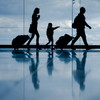 Silhouetten einer Familie mit Rollkoffern am Flughafen
