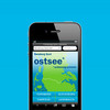 Smartphone zeigt Website flensburg-fjord.de vor blauem Hintergrund