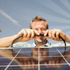 Ein blonder Mann schliesst zwei Kabel eines Solarmodules aneinander