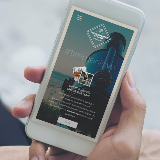 Hand hält Smartphone mit geöffneter Timmendorfer Strand Homepage